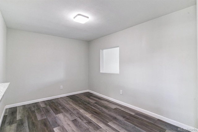 empty room featuring dark wood-type flooring and baseboards