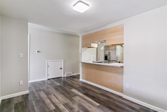 kitchen featuring stainless steel fridge, light countertops, dark wood finished floors, and baseboards