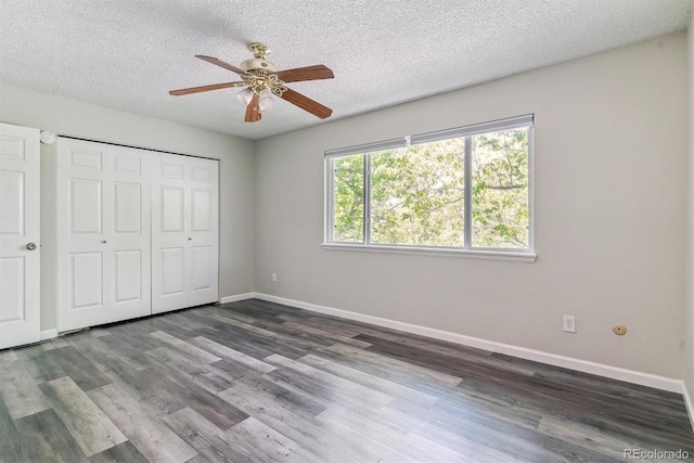 unfurnished bedroom featuring dark wood-style flooring, baseboards, a closet, a textured ceiling, and ceiling fan
