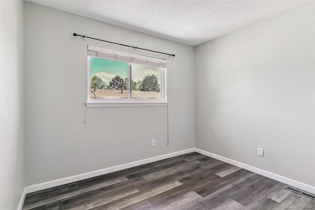 empty room featuring dark wood-type flooring, a textured ceiling, and baseboards