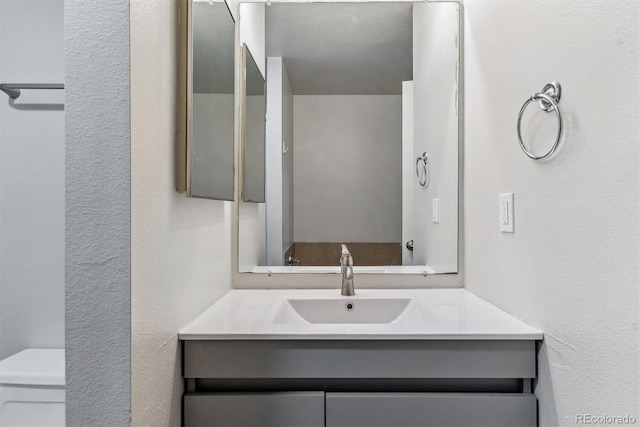 half bathroom with vanity and a textured wall