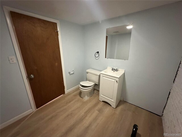 11623 E Virginia Dr, Aurora, CO 80012 - half bathroom with toilet, vanity, wood finished floors, and baseboards