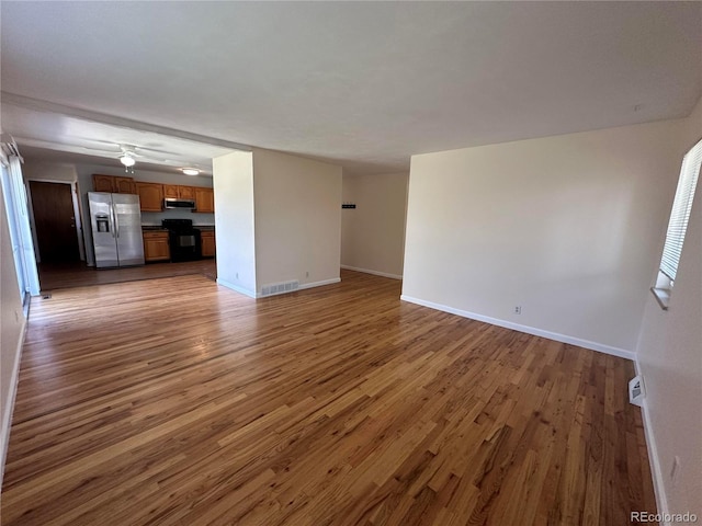 11623 E Virginia Dr, Aurora, CO 80012 - unfurnished living room with baseboards, wood finished floors, and visible vents