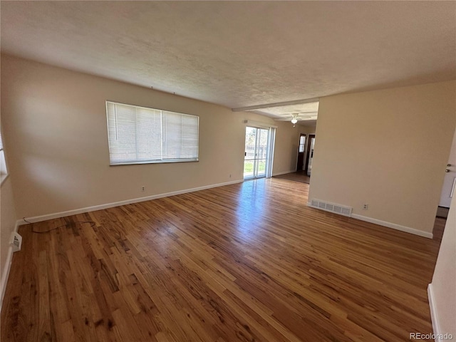 11623 E Virginia Dr, Aurora, CO 80012 - unfurnished room with baseboards, wood finished floors, visible vents, and a textured ceiling
