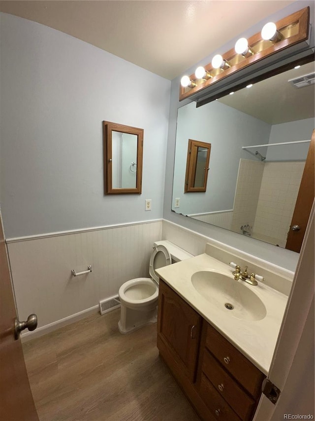 11623 E Virginia Dr, Aurora, CO 80012 - full bath with wainscoting, visible vents, wood finished floors, a shower, and vanity