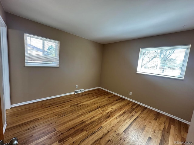 11623 E Virginia Dr, Aurora, CO 80012 - empty room featuring wood finished floors, visible vents, and baseboards