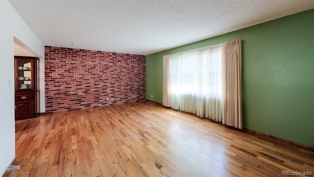 1813 Pikes Peak St, Erie, CO 80516 - unfurnished living room featuring wood finished floors, brick wall, and a textured ceiling