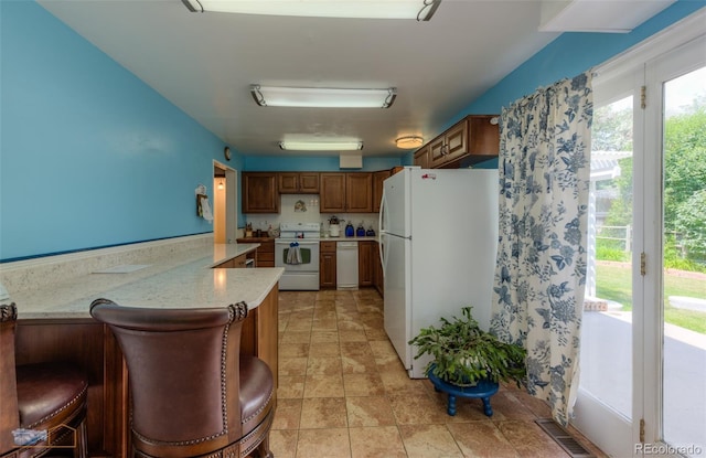 1813 Pikes Peak St, Erie, CO 80516 - kitchen with white appliances, light countertops, brown cabinets, a peninsula, and light stone finish floors