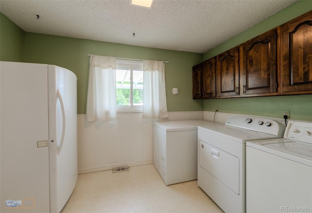 1813 Pikes Peak St, Erie, CO 80516 - laundry room featuring separate washer and dryer, a wainscoted wall, cabinet space, and a textured ceiling