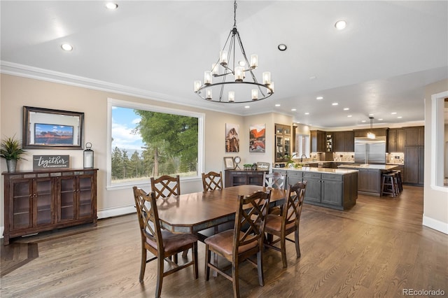 dining area with a baseboard heating unit, a notable chandelier, wood-type flooring, sink, and ornamental molding