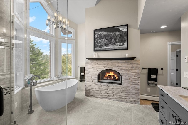 bathroom featuring a baseboard heating unit, vanity, a fireplace, a notable chandelier, and separate shower and tub