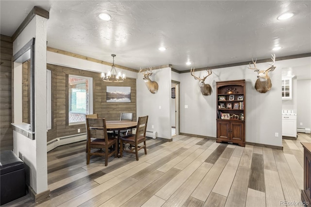 dining space featuring a baseboard heating unit, a notable chandelier, and light hardwood / wood-style flooring