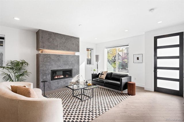 living room with a high end fireplace and light wood-type flooring