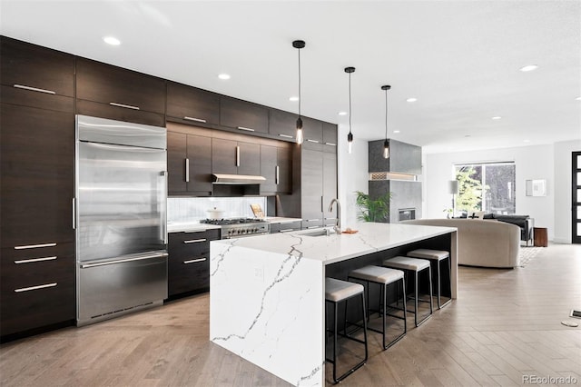 kitchen featuring appliances with stainless steel finishes, sink, pendant lighting, a breakfast bar area, and an island with sink