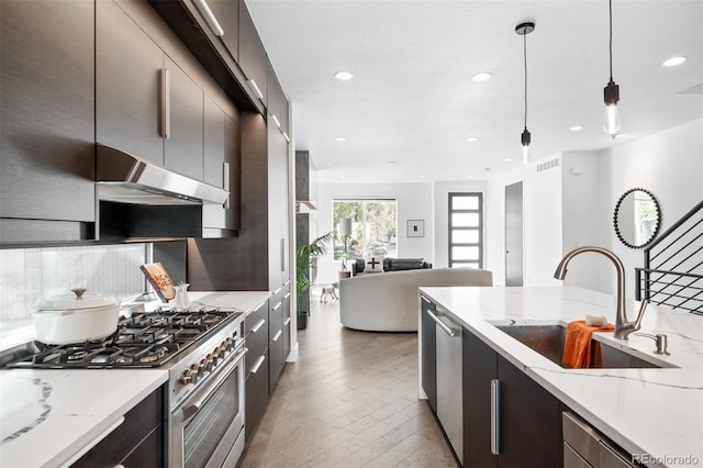 kitchen featuring appliances with stainless steel finishes, decorative light fixtures, light stone counters, and sink