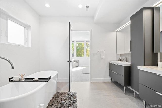 bathroom featuring tiled tub, tile patterned flooring, and vanity