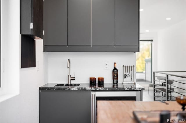 kitchen featuring gray cabinets, dark stone countertops, and sink