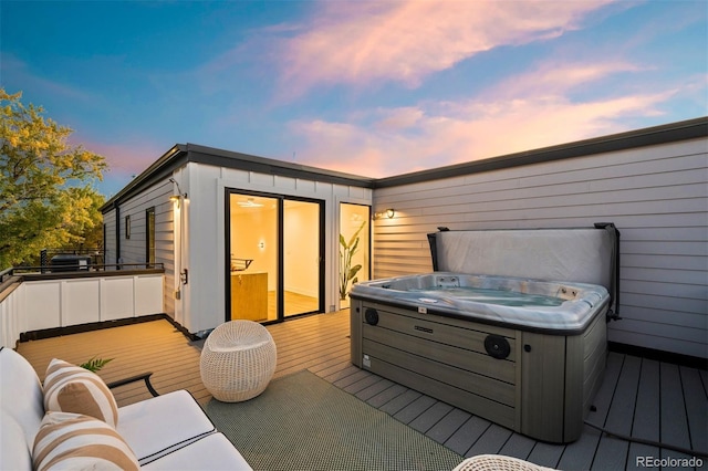 deck at dusk featuring a hot tub