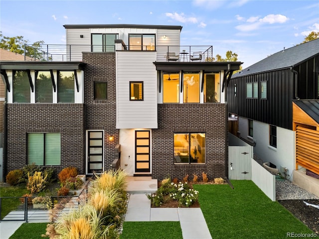 modern home featuring a balcony and a front yard