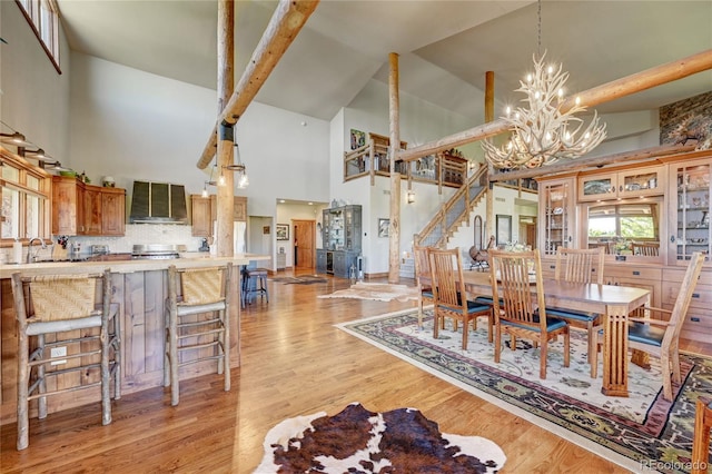 dining area with a notable chandelier, high vaulted ceiling, and light hardwood / wood-style floors