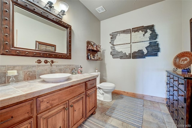 bathroom with vanity, decorative backsplash, and toilet