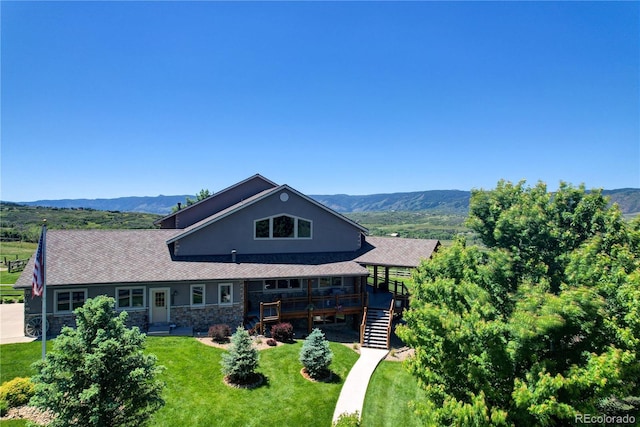 view of front of property with a front yard and a deck with mountain view