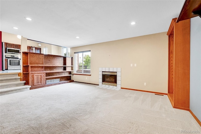 13008 Grove Way, Broomfield, CO 80020 - unfurnished living room featuring a tile fireplace, light carpet, baseboards, recessed lighting, and stairs