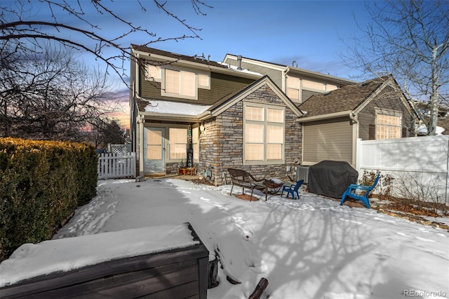 snow covered back of property featuring an outdoor fire pit and a jacuzzi