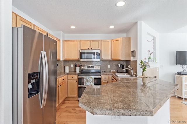 kitchen with appliances with stainless steel finishes, light brown cabinets, and kitchen peninsula