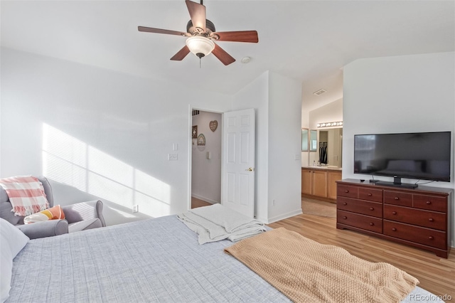 bedroom featuring ceiling fan, ensuite bath, vaulted ceiling, and light hardwood / wood-style flooring