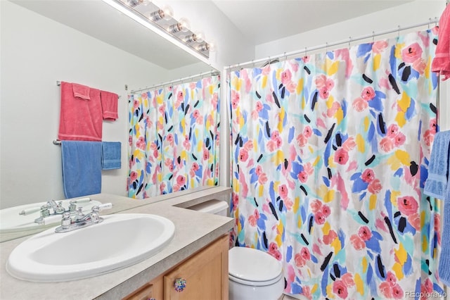 bathroom featuring vanity, walk in shower, and toilet