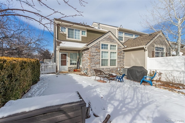 snow covered back of property with a hot tub and a fire pit