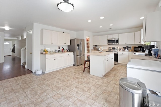 kitchen featuring white cabinetry, a breakfast bar, a kitchen island, and appliances with stainless steel finishes