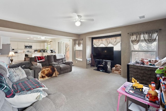 carpeted living room with ceiling fan and a healthy amount of sunlight