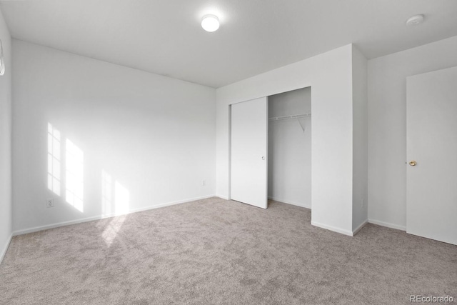 unfurnished bedroom with light colored carpet and a closet