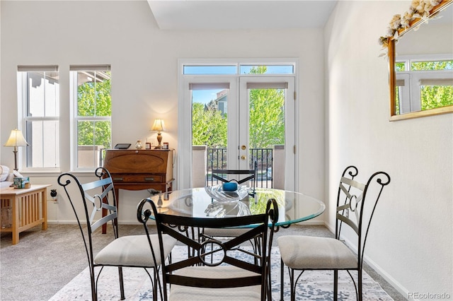 dining room featuring plenty of natural light, light colored carpet, baseboards, and french doors