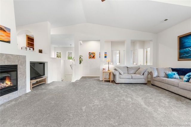 carpeted living room with vaulted ceiling and a tile fireplace