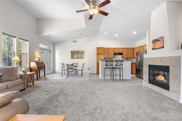 living room featuring ceiling fan, light carpet, high vaulted ceiling, recessed lighting, and a tiled fireplace
