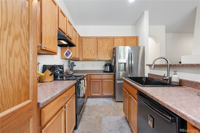 kitchen featuring under cabinet range hood, black appliances, a sink, stone finish flooring, and light countertops