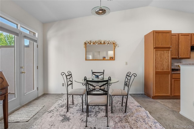 dining area with light colored carpet, lofted ceiling, and baseboards