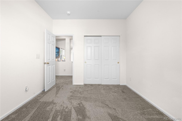 unfurnished bedroom featuring carpet floors, baseboards, and a closet