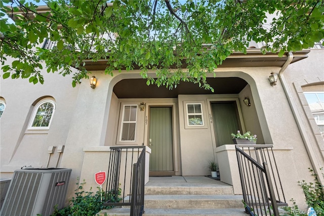 property entrance featuring central AC and stucco siding