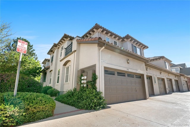 view of side of home with stucco siding, concrete driveway, and a tile roof