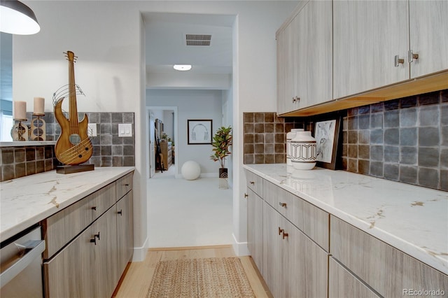 kitchen with light stone counters, light brown cabinets, light wood-type flooring, and tasteful backsplash