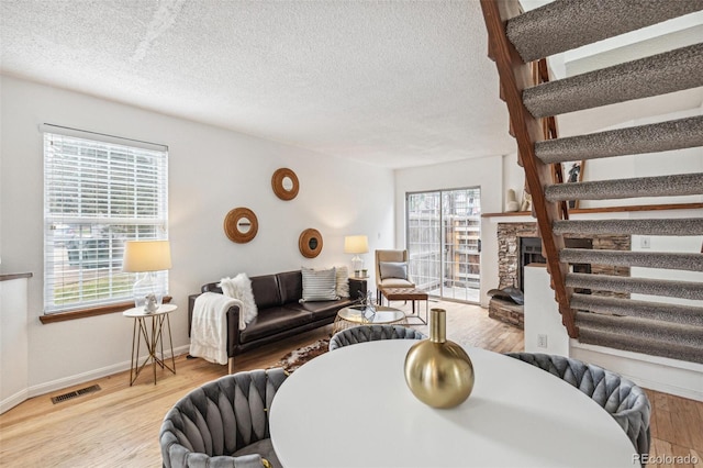 living room featuring a textured ceiling, light wood-type flooring, and a fireplace