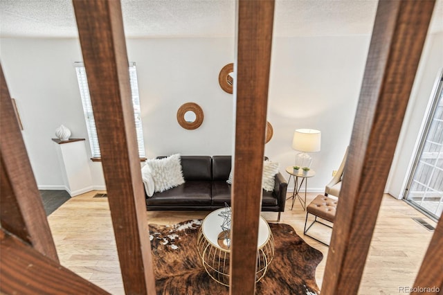 interior space featuring decorative columns, light hardwood / wood-style floors, and a textured ceiling