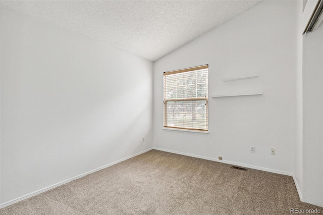 carpeted empty room with vaulted ceiling and a textured ceiling