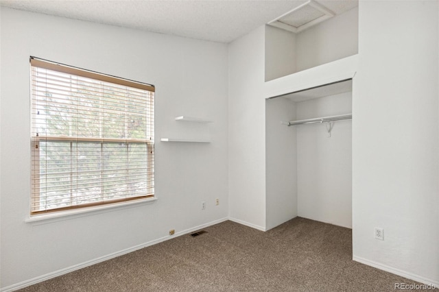 unfurnished bedroom with a closet, carpet flooring, multiple windows, and a textured ceiling