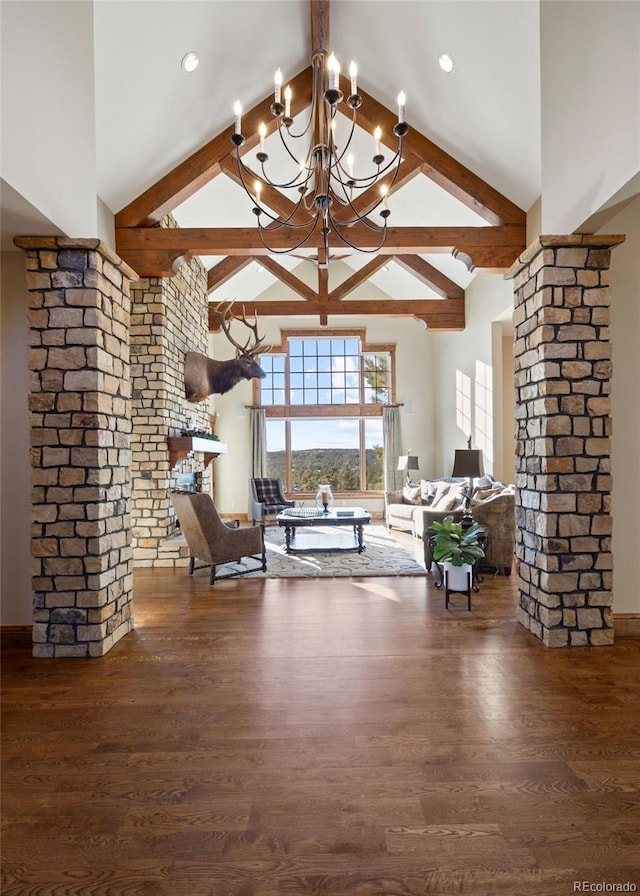 living area featuring beam ceiling, high vaulted ceiling, wood finished floors, and ornate columns