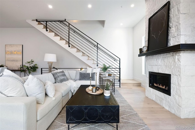 living room with a stone fireplace and light hardwood / wood-style flooring